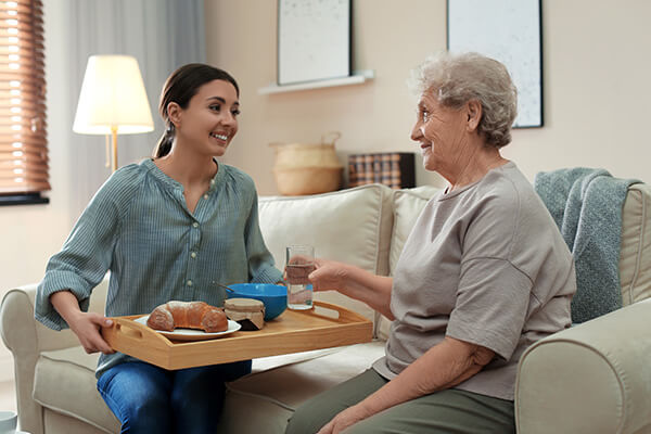 Home nurse helping older woman with food