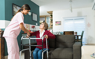 Home nurse helping older woman stand